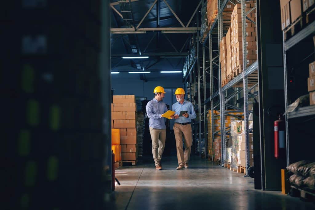 two business men in formal wear with protective yellow helmets walking and talking about business. Making business decision.