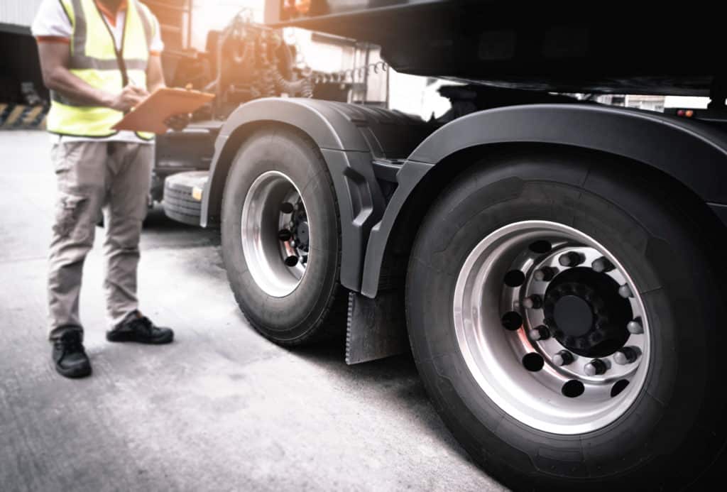 Worker checking tires on semi truck