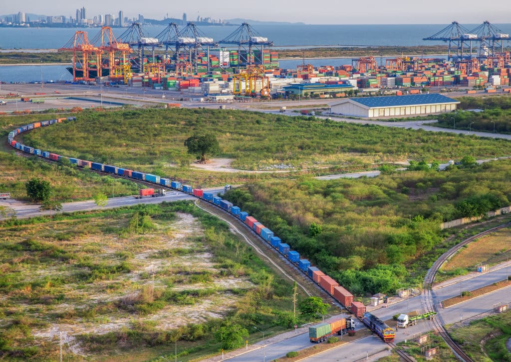 Train loaded with many colorful containers leaves shipping area