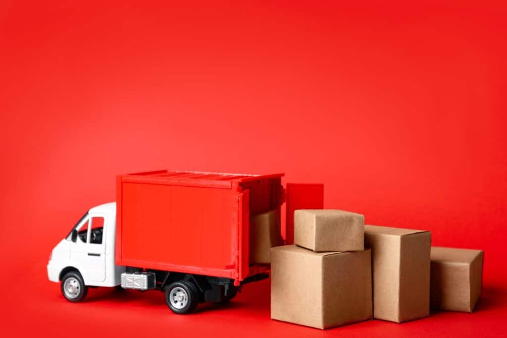 An image of a red toy truck with brown packages coming out of the truck's trailer.