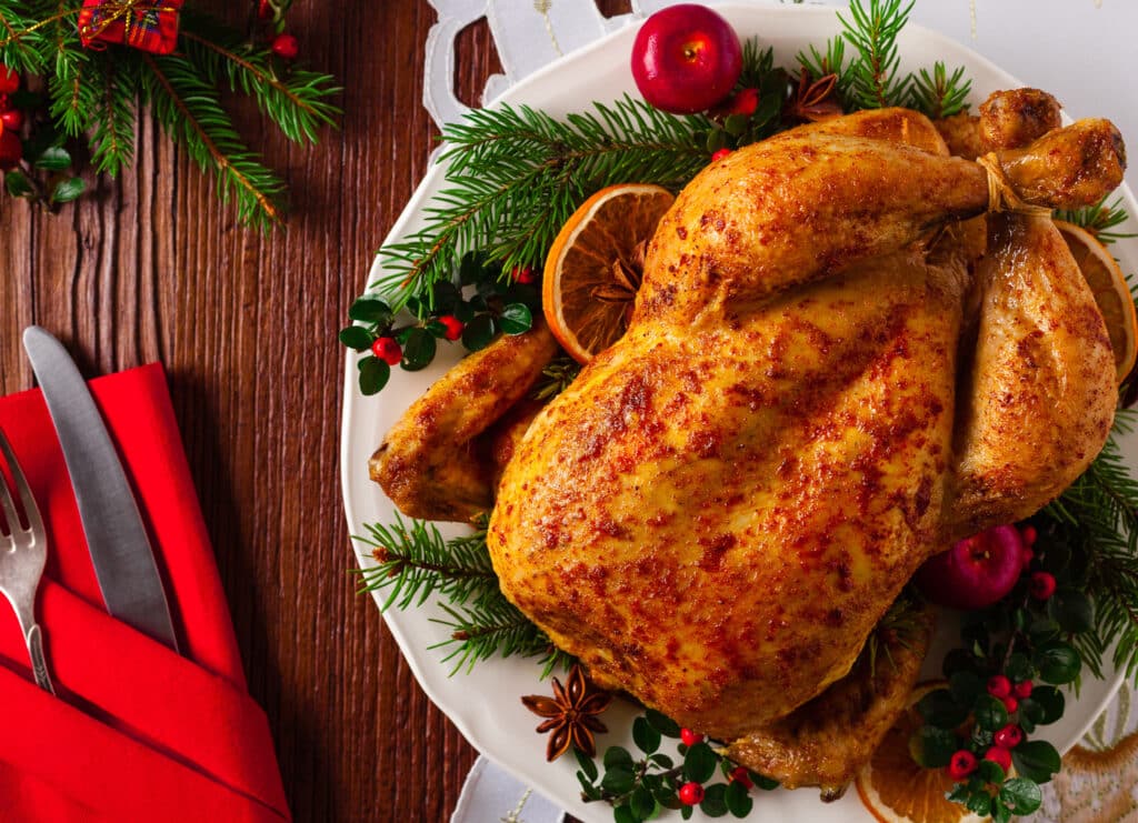 Roasted whole chicken with Christmas decoration. Wooden background. Top view.