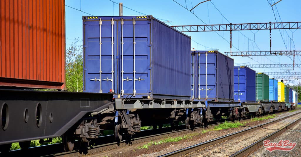 A photo of blue, yellow, orange, and green intermodal containers on rail tracks.
