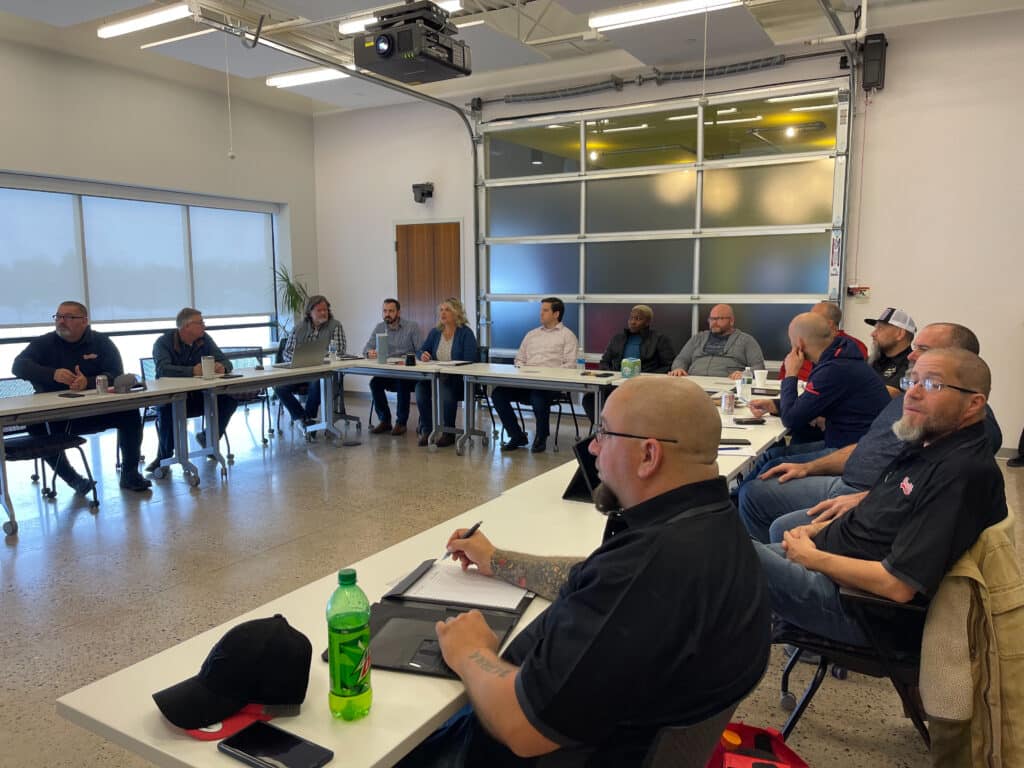 A photo of Bay & Bay team members and Bay & Bay truck drivers working together to talk with one another and listen to the driver's needs and enhance company culture.