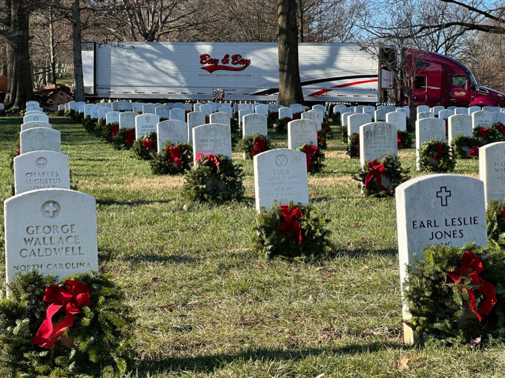 A photo of a Bay & Bay truck with a Bay & Bay refrigerated trailer attached parked at Arlington National Cemetery delivering wreaths for Wreaths Across America.
