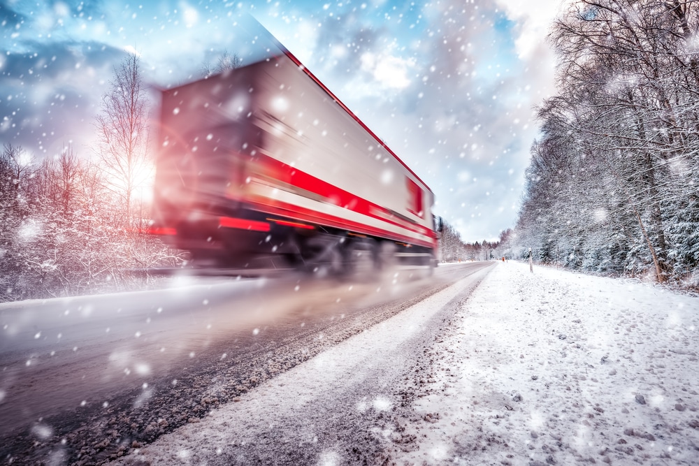 A photo of a red and white truck driving down a snowy road getting home for the holidays.